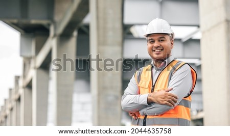 Asian engineer handsome man or architect looking construction with white safety helmet in construction site. Standing at highway concrete road site. Royalty-Free Stock Photo #2044635758