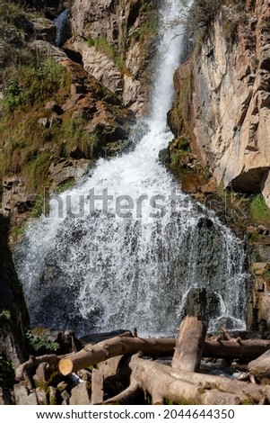 Close-up of a powerful waterfall in high quality. Side view of a sun-drenched waterfall in the wild. A large stream of water pours down from the mountain.