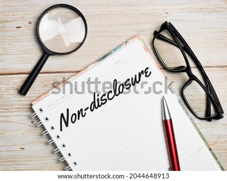 Non-disclosure written on note book with pen,magnifying glass and eye glasses.