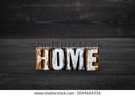 HOME. White wooden letters on a dark wooden background.