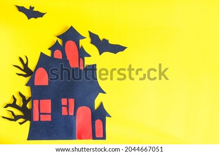 Handmade on the theme of Halloween. A castle with red windows and bats on a bright yellow background of kopi space.