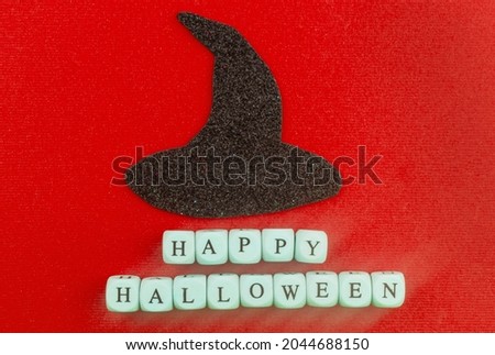 Black witch hat and inscription Happy Halloween on a red background.