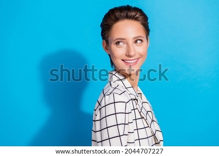 Photo of confident cute young lady wear plaid outfit smiling looking back empty space isolated blue color background