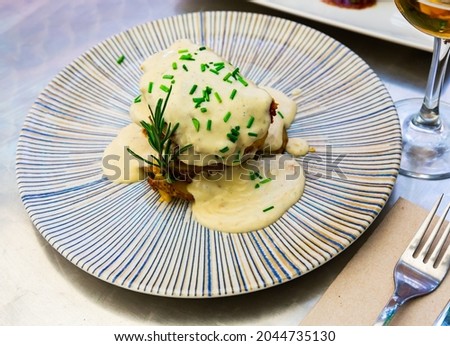 Dish of appetizing pork with a delicious Roquefort cheese sauce with potatoes and herbs, decorated with a sprig of ..rosemary