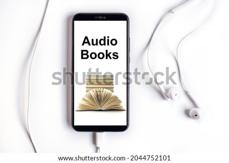 Smartphone with earphones and Audiobooks collection on screen