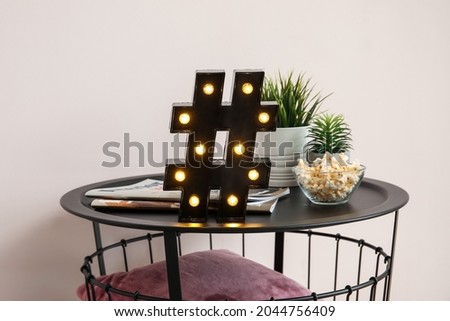 Stylish decor and bowl with popcorn on table near light wall