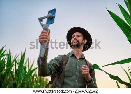 Traveler man backpacker blogger wearing felt hat with electronic manual phone stabilizer gimbal takes a selfie and shoots video blog outdoors 