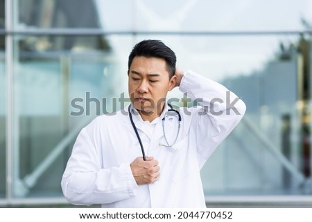 Asian doctor is tired after work, depressed and disappointed with the work done on the street near the clinic