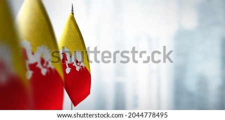 Small flags of Bhutan on a blurry background of the city.