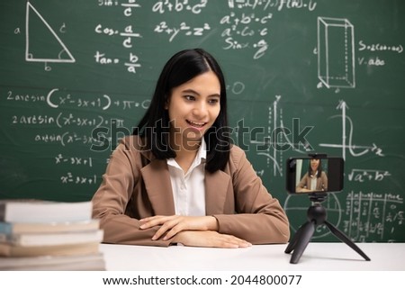 Young asian teacher woman sitting and video conference with student. Female teacher training the mathematics in classroom from live stream with smartphone online course.