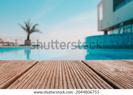 Empty wooden deck with swimming pool , Beautiful minimalist pool side view with clear blue sky . Vintage filter color apply . Royalty-Free Stock Photo #2044806755