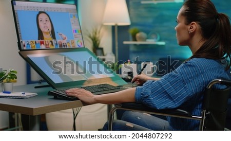 Photography artist with handicap using touch screen for pictures retouching at studio. Invalid photographer working with editing software and graphic tablet for photo retouch in wheelchair