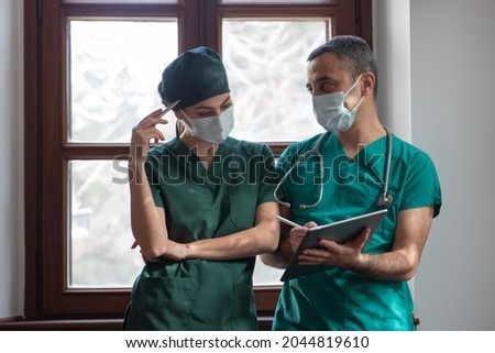 Portrait Of Female And Male Doctors Discussing With Positive Emotions In Clinic Using Digital Tablet And Stylus