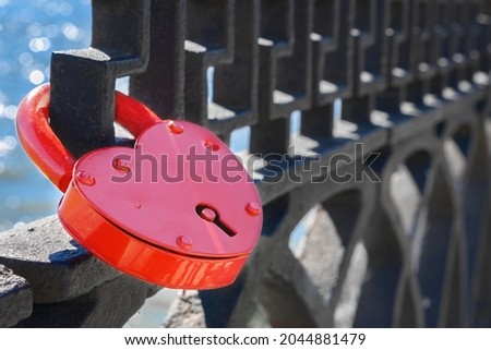 Red lock of love on a metal lattice. Close-up