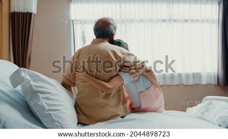 Little girl Asian granddaughter visiting hug sick senior grandfather hospitalized sit on hospital bed in patient room. Rehabilitation activity, health insurance, healthcare and medicine concept. Royalty-Free Stock Photo #2044898723