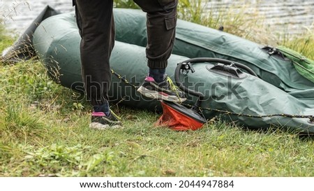 a man pumps a rubber boat with an air pump. nature recreation travel