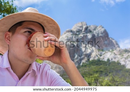 Traveling man drinks in a jar overlooking the mountain scenery, Latin tourist enjoys the scenery in the mountains. Concept of hiking