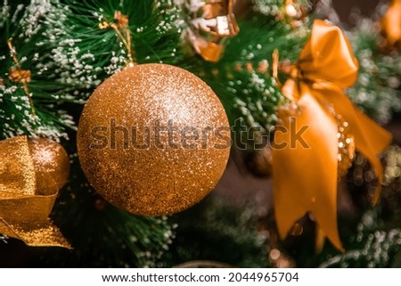 Close-up of a golden Christmas tree toy hanging on a branch against a bokeh background. Decorated Christmas tree.
