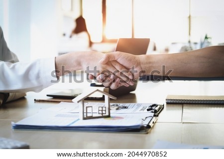 Focus on the congratulatory handshake. The real estate agent agrees to buy the home to the customer at the agent's office. conceptual agreement.