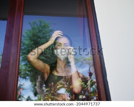 woman in the window wearing a medical mask ban quarantine