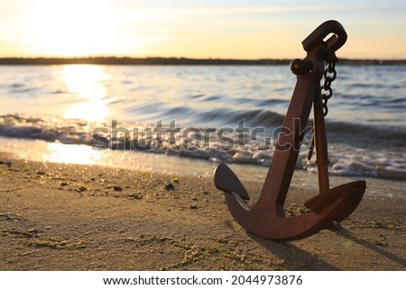 Wooden anchor on shore near river at sunset Royalty-Free Stock Photo #2044973876