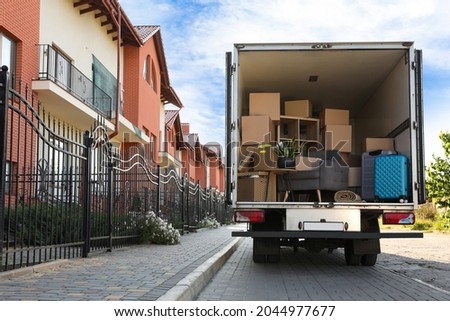 Van full of moving boxes and furniture near house Royalty-Free Stock Photo #2044977677