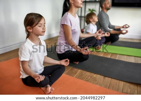 Calm Caucasian family with children sit on mats practice yoga have meditation session together. Mindful parents with kids meditate together at home, breathe fresh air relieve negative emotions. Royalty-Free Stock Photo #2044982297