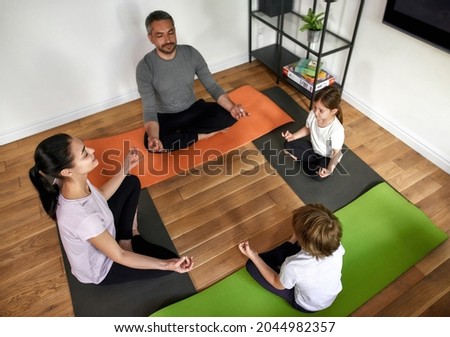 Top down view of calm parents with teen kids practice yoga meditate with mudra hands with eyes closed. Family with teenage children sit in lotus pose have meditation session relieve negative emotions. Royalty-Free Stock Photo #2044982357