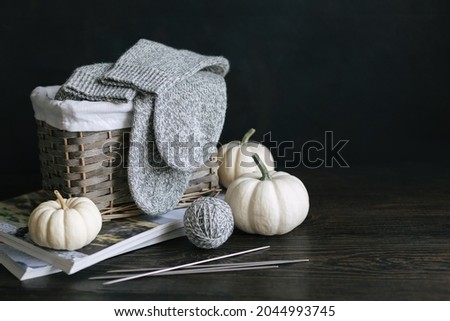 Hand knitting socks with needles, yarn balls and pumpkins on a dark wooden background.  Concept for handmade and hygge slow life.  