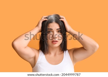 Stressed woman with graying hair on color background Royalty-Free Stock Photo #2044999787
