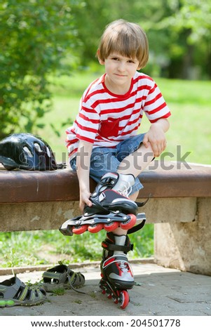the child put on roller skates on a bench in the summer Park