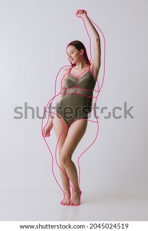 Beautiful woman with fit body in inner wear posing isolated over gray studio background. Line doodles around body. Healthy lifestyle. Concept of healthy eating, dieting, loosing weight, fitness, ad Royalty-Free Stock Photo #2045024519