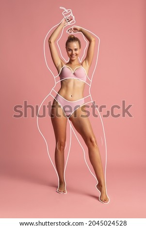 Young beautiful woman in inner wear with perfect body shape and white lines around body before loosing weight isolated over pink background. Concept of healthy eating, dieting, weight, fitness, ad Royalty-Free Stock Photo #2045024528