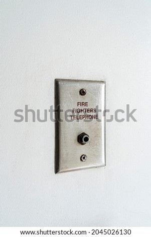 Small fire fighters telephone plug on the white wall in a residence.