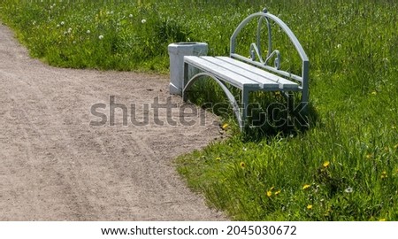 a lonely bench in the park for recreation. trash can next to the bench