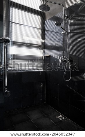  Closeup of a shower in a black bathroom, with sunlight coming in from the window