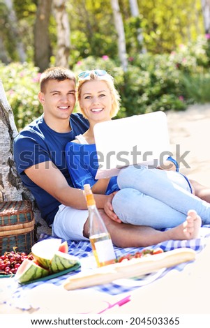 A picture of a young happy couple using laptop at the beach