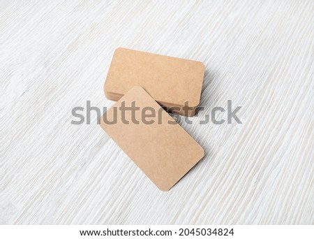 Blank kraft business cards on light wood table background. Mockup for branding identity. Template for graphic designers portfolios.