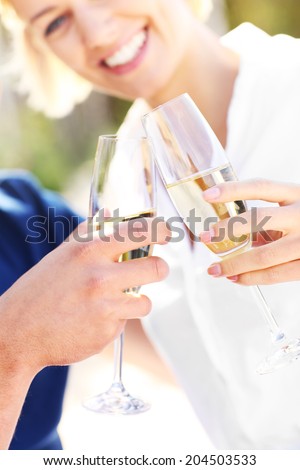 A picture of an adult couple with glasses of champagne at the beach