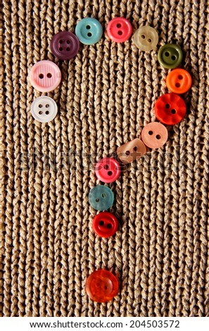 question mark from made in colorful buttons on knitted natural background Royalty-Free Stock Photo #204503572