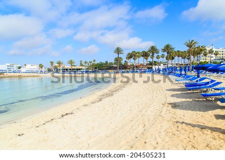 Blue beach umbrellas and sunbeds on Sandy Beach in Ayia Napa, Cyprus Royalty-Free Stock Photo #204505231