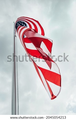 USA America flag waving in the wind over cloudy sky low angle view close up.