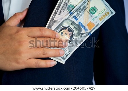 Dogecoin coin DOGE included with Cryptocurrency and stack 5 five US dollar Money American on hand business man wearing a blue suit. Filed and put and give to me.