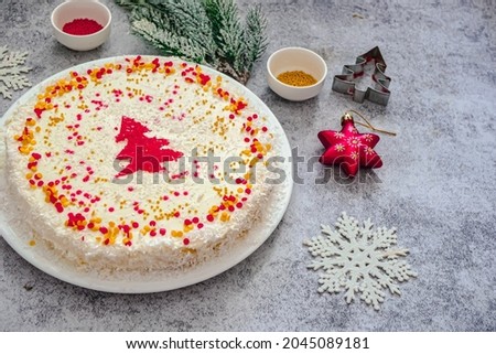 
Homemade New Year's cake with white and cream and gold and red sprinkles. Cake with christmas decor in red and gold background