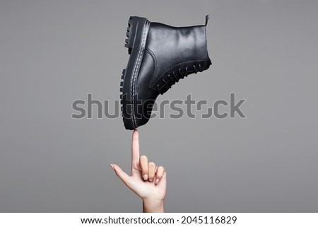 woman's hand holding Black boot. fashion shoes. stylish photo in the studio