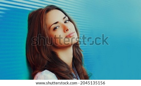 Portrait of beautiful young brunette woman on blue background