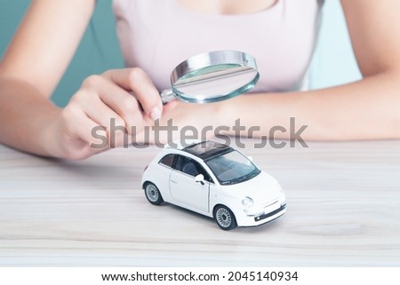 woman with a magnifying glass looks at the car. car search concept Royalty-Free Stock Photo #2045140934