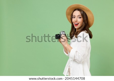Side view fun traveler tourist woman in casual clothes hat take picture on retro vintage photo camera isolated on green background Passenger travel abroad weekends getaway Air flight journey concept. Royalty-Free Stock Photo #2045144708