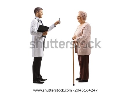 Young male doctor showing a mobile phone to a mature female patient isolated on white background 