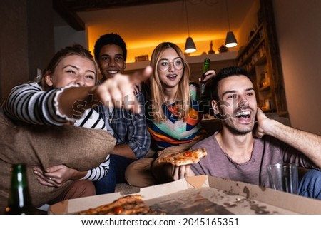 Best friends sitting at home watching  movie .Joying in tv show and eating pizza. Royalty-Free Stock Photo #2045165351